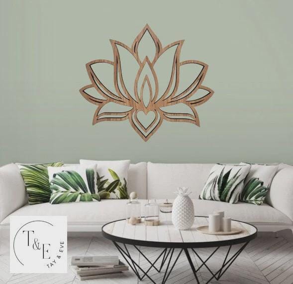 Wooden lotus wall art above a white sofa with decorative pillows in a living room setting.